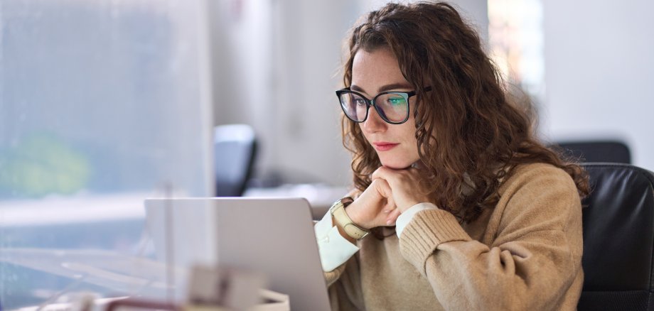 Frau sitzt vor Laptop, z. B. für eine Online Konferenz oder ein Seminar